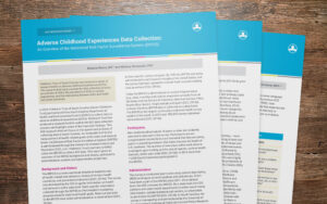 Samples of adverse childhood experience research brief fanned over a wooden desk.