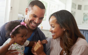 Couple laughing with their young daughter.