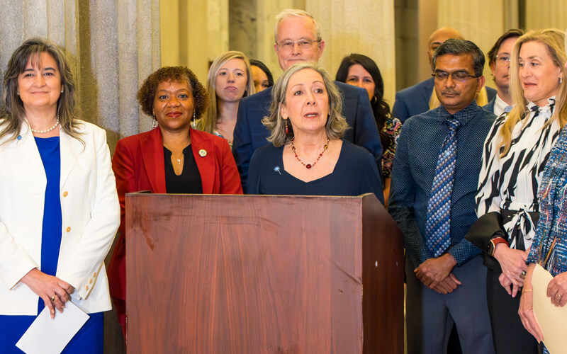 Sue speaking at podium in the Statehouse in 2025.