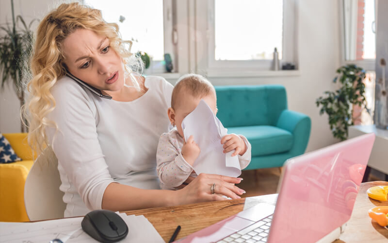 Mother-struggleing-with-baby-while-on-the-phone-with-laptop