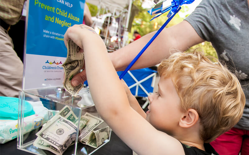 A child inserts his donation into a donation box at Soda City in Columbia, South Carolina.