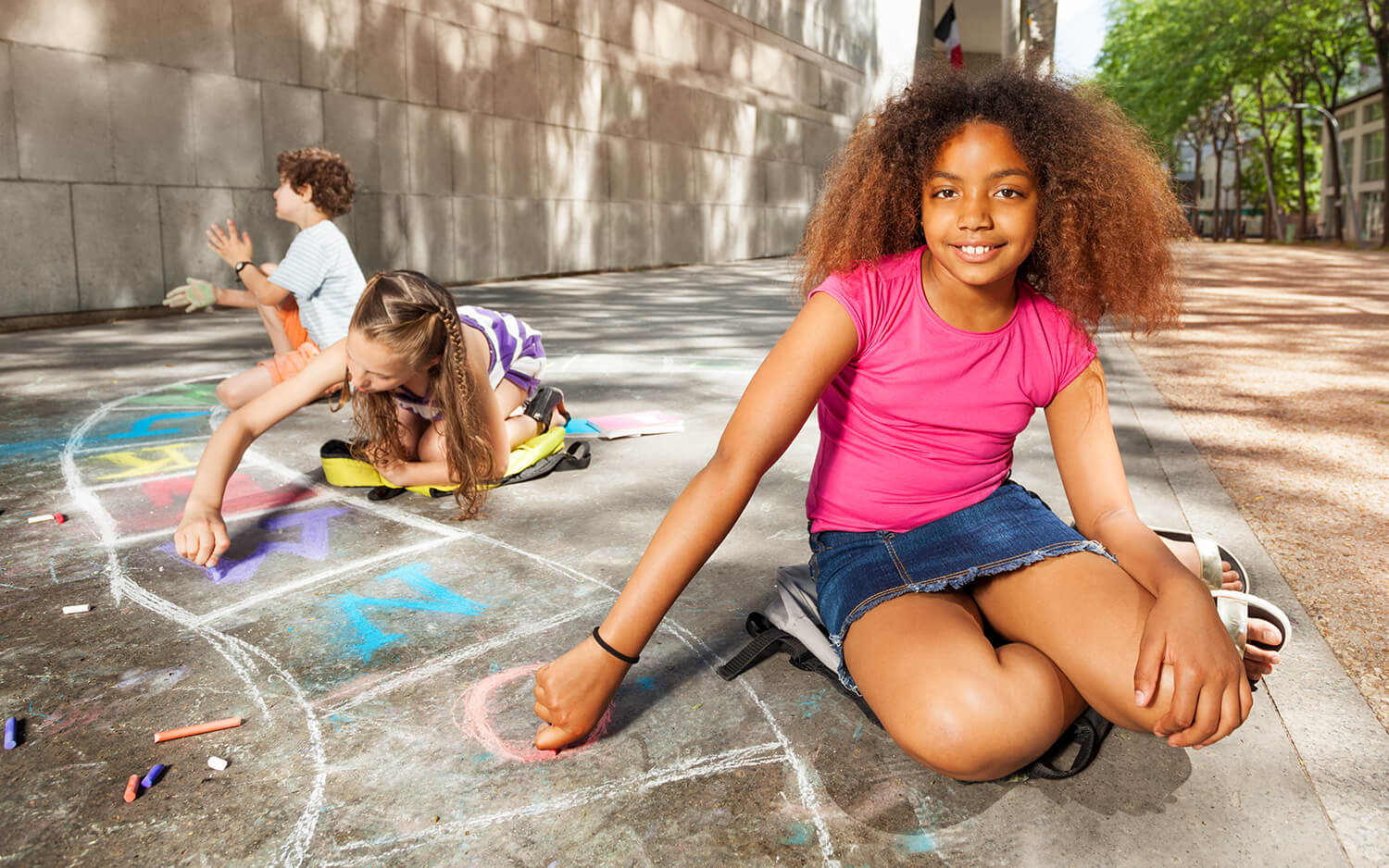 Girls drawing hopscotch with chalk game smiling.