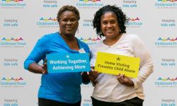 Attendees-pose-with-signs-in-front-of-Childrens-Trust-banner
