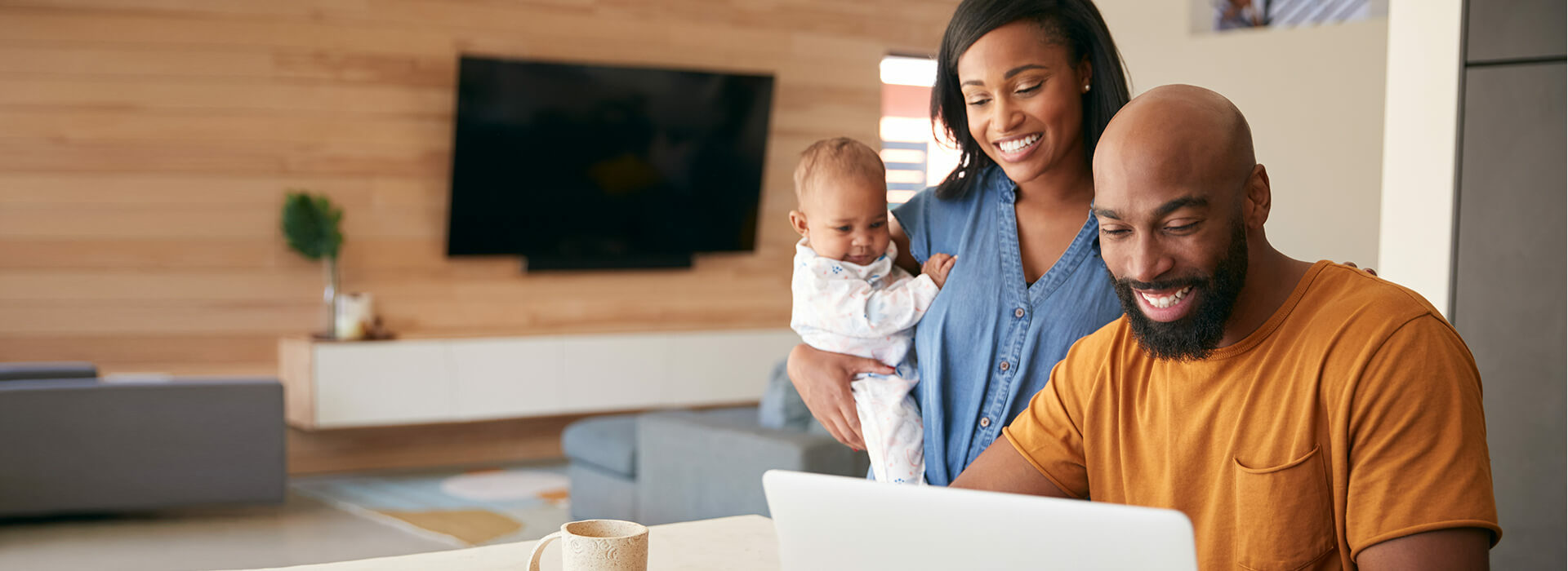 Black family with baby looking at laptop.