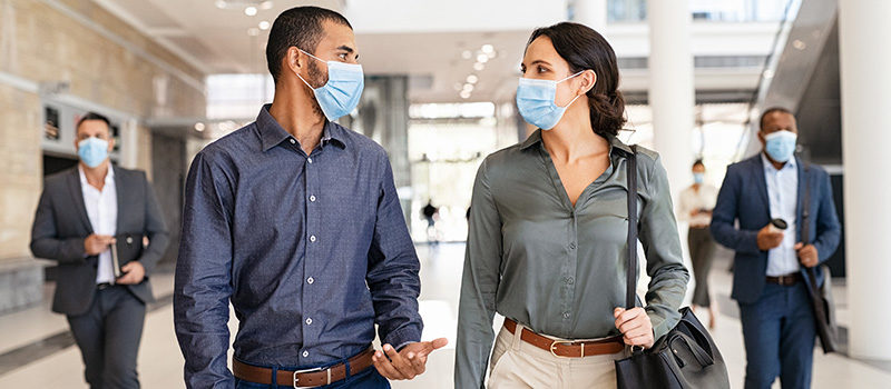Businesspeople talking while walking with face masks
