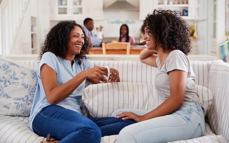 Mother Talking With Teenage Daughter On Sofa.