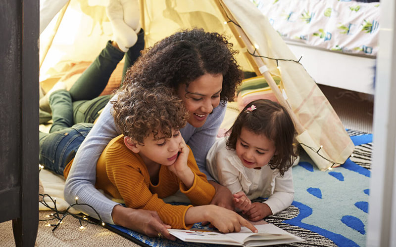Mother reading to kids under tent in their bedroom.