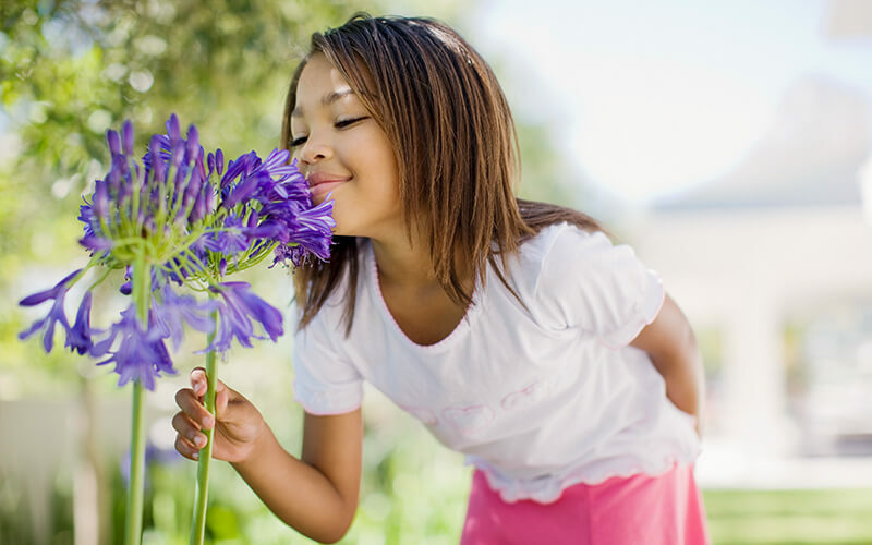 Young girl smelling a flower.