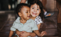 Young sister hugging her younger brother