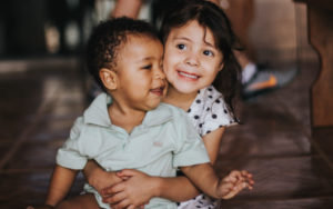 Young sister hugging her younger brother