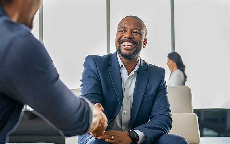 Black businessman shaking hands with another business partner.
