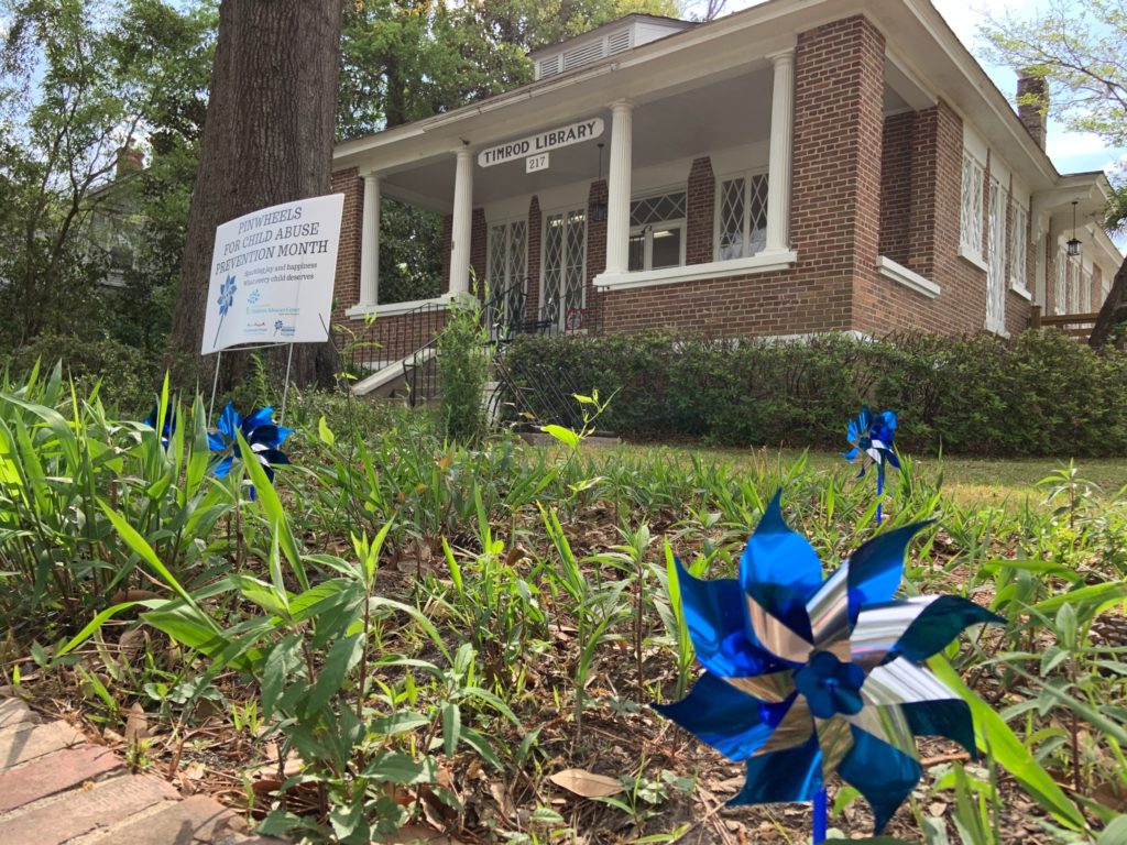 A library displaying a pinwheel and sign that says: "April is Child Abuse Prevention Month"